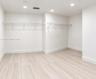 Walk-in storage space featuring wood-finish flooring, white walls, and built-in white wire shelving with integrated lighting