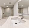 Bathroom featuring a vanity with an integrated rectangular sink and polished chrome faucet, stone-finish countertop, frameless glass shower enclosure,