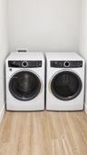 Laundry area featuring front-loading washer and dryer units set upon wood-finish flooring