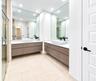 Dual floating vanities with wood-finish MASTERs cabinetry, rectangular vessel sinks, expansive wall-to-wall mirrors, and matte black fixtures, complem
