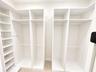 Custom walk-in storage featuring white built-in cabinetry, adjustable shelving, integrated garment rods, and tiled flooring