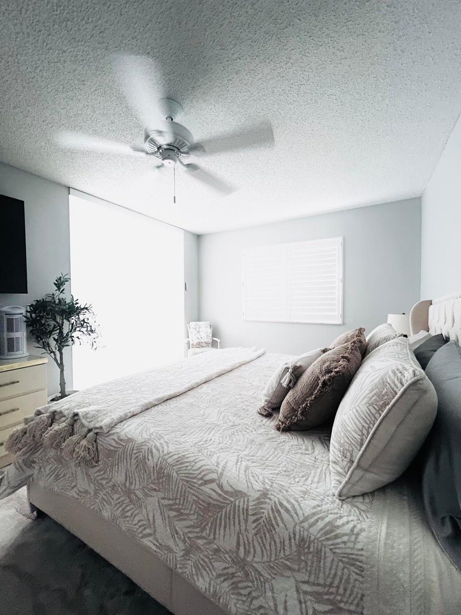 Spacious interior room featuring a ceiling fan, window with horizontal blinds, light-colored walls, and textured ceiling