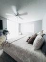 Spacious interior room featuring a ceiling fan, window with horizontal blinds, light-colored walls, and textured ceiling