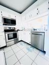 Kitchen featuring white cabinetry with dark hardware, a stainless steel range with an over-the-range microwave, a stainless steel dishwasher, and whit
