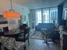 Floor-to-ceiling windows, wood-finish flooring, and a linear pendant light fixture