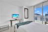 Floor-to-ceiling sliding glass doors, neutral tile flooring, and a private balcony featuring a metal railing