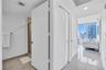 Hallway featuring polished tile flooring, white interior doors, built-in storage closets, recessed lighting, and floor-to-ceiling windows