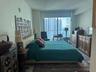 Floor-to-ceiling glass sliding doors opening to a balcony, neutral wall finishes, and overhead lighting