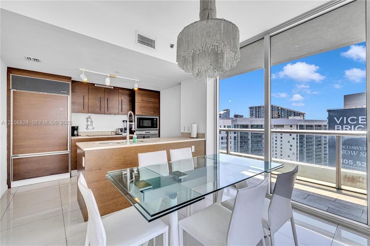 Kitchen featuring wood-finish cabinetry, stone countertops, integrated refrigerator, and porcelain tile flooring, accompanied by floor-to-ceiling wind
