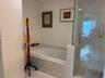 Bathroom featuring a deep-soaking bathtub with tile surround and a separate glass-enclosed shower with installed grab bar