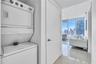 Stacked laundry unit, gloss-finish tile flooring, and floor-to-ceiling windows