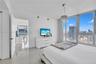 Floor-to-ceiling windows featuring urban scenery, polished tile flooring, and a contemporary drum pendant light fixture