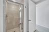Walk-in shower featuring large-format neutral wall tile, a metal-framed glass enclosure, and a chrome single-handle mixing valve