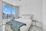 Floor-to-ceiling glass sliding doors opening to a balcony, polished tile flooring, and neutral wall finishes