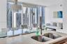 Floor-to-ceiling windows, stone-surfaced kitchen island with a double-basin stainless steel sink, and high-rise urban scenery