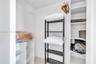 Storage closet featuring built-in white shelving units, a suspended clothing rod, and tiled flooring