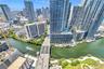 Aerial perspective of a high-density urban environment featuring a deep-water canal, paved bridge infrastructure, multiple glass-facade skyscrapers, a