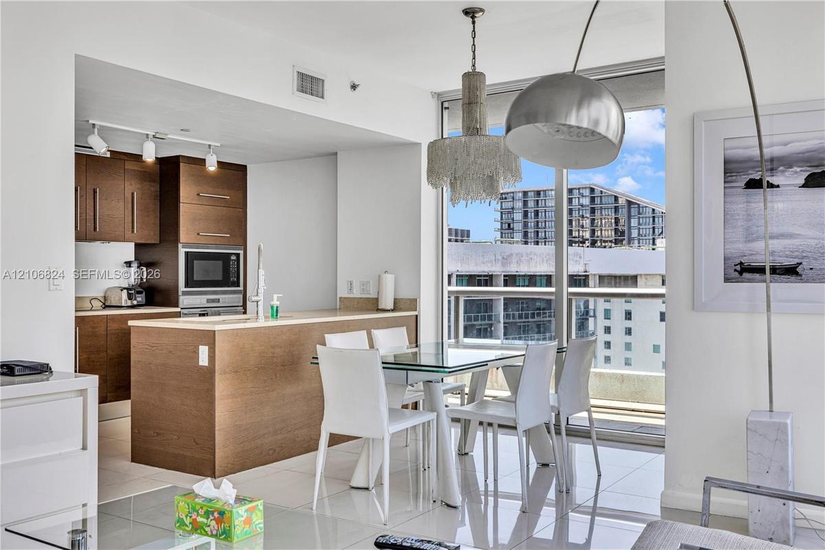 Kitchen featuring wood-finish cabinetry, built-in wall oven and microwave, solid surface countertops, track lighting, and floor-to-ceiling windows