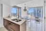 Kitchen featuring wood-finish cabinetry, neutral stone-finish countertops, and an undermount double-basin sink with a gooseneck faucet, set against fl