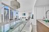 Floor-to-ceiling windows, tile flooring, tiered crystal chandelier, kitchen peninsula with stone-finish countertop, and stainless steel pull-down fauc