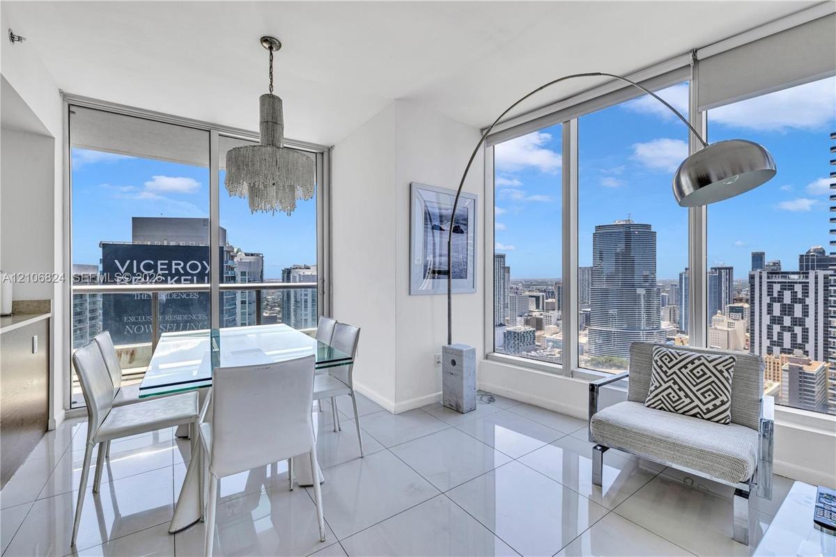 Floor-to-ceiling glass windows, polished tile flooring, and a decorative pendant chandelier