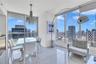 Floor-to-ceiling glass windows, polished tile flooring, and a decorative pendant chandelier