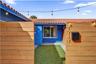 Residence 1747 (Left Side) – Private courtyard entrance featuring wood privacy fencing, and low-maintenance artificial turf and hurricane impact glass