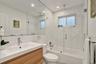 Residence 1747 (Left Side) Bathroom 2 featuring a wood-finish floating vanity with an integrated sink, polished chrome faucet, frameless glass-enclose