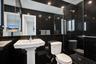 En-suite with full-height black wall tiling, glass-enclosed walk-in shower with grid-patterned floor tile, white pedestal sink, and recessed ceiling l