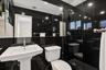 En-suite with full-height black wall tiling, glass-enclosed walk-in shower with grid-patterned floor tile, white pedestal sink, and recessed ceiling l