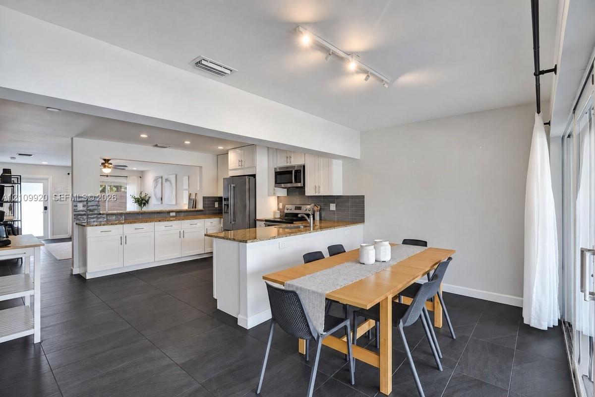 Residence 1747 (Left Side) – Kitchen featuring white cabinetry, granite countertops, stainless steel appliances, and a spacious dining area with hurri