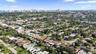 Aerial perspective of residential property featuring a backyard swimming pool, screened-in lanai, and tile roof, positioned within an established coas