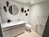 Bathroom featuring a vanity with stone-top surfacing, undermount basin, circular wall mirror, polished chrome fixtures, and tile flooring