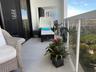 Private balcony featuring light-toned stone flooring and a glass-panel railing with white framing