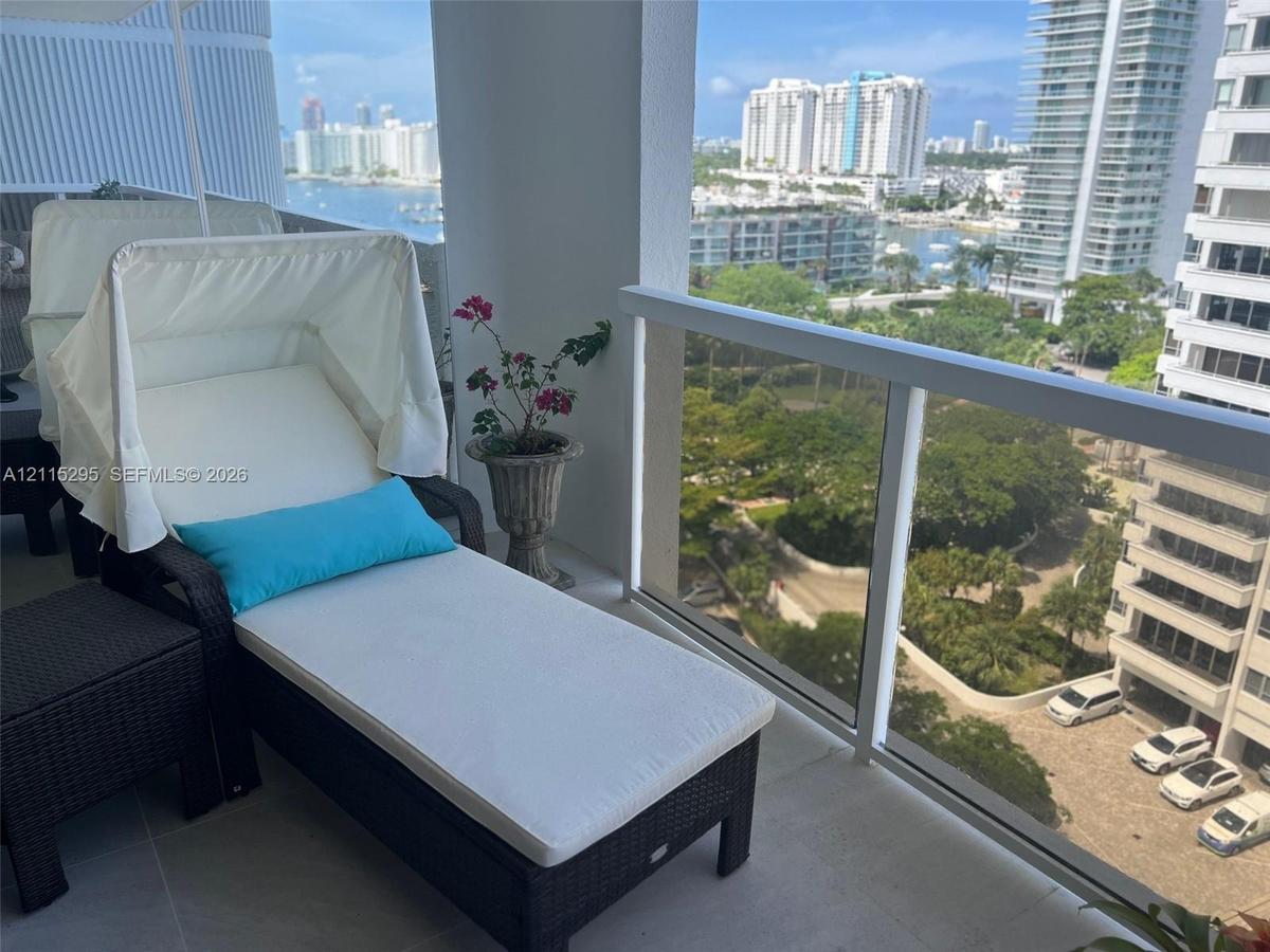 Covered balcony featuring neutral tile flooring and a glass panel railing