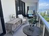 Covered private balcony featuring a glass-panel railing, light-toned flooring, and expansive water scenery