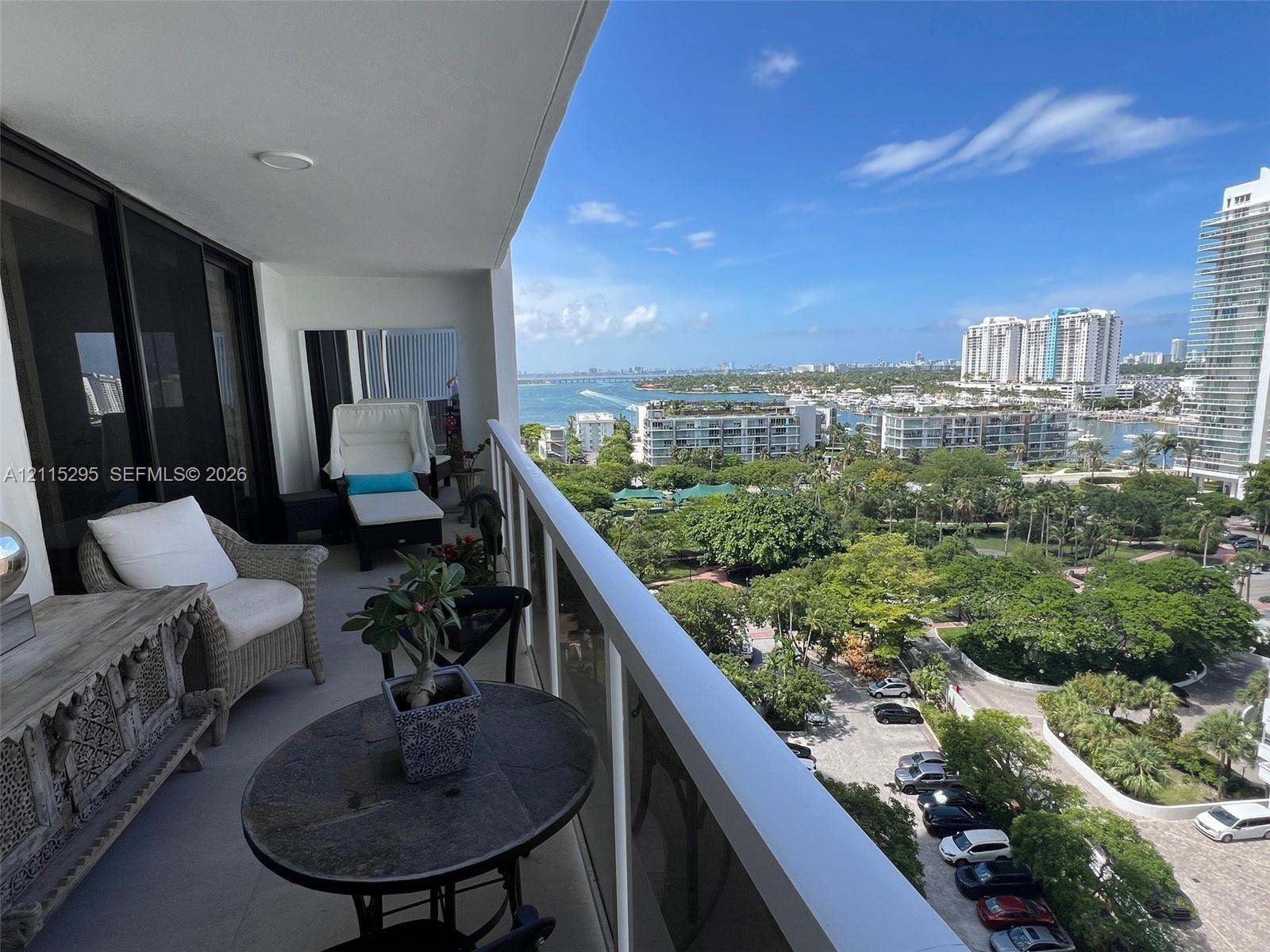 Covered balcony featuring a metal railing, recessed lighting, and expansive water and urban scenery