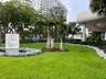 Landscaped grounds featuring a manicured lawn, established palm trees, mature canopy trees, and low-lying groundcover plantings