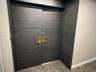 Dark-toned, horizontal-grain double entry door featuring brushed metal hardware and integrated unit numbering