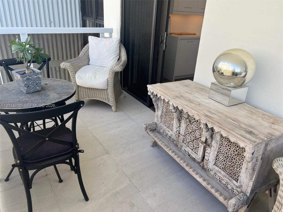 Covered balcony featuring large-format stone-finish floor tiles and white metal railing
