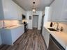 Kitchen featuring minimalist flat-panel cabinetry, solid surface countertops, under-cabinet lighting, stainless steel appliances, and wood-finish floo