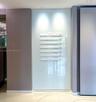 Wall-mounted directory signage featuring white tiered lettering against a backlit, floor-to-ceiling glass panel, set within a neutral-toned alcove wit
