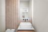 Half Bath off living room. Wall-mounted matte black faucet, white rectangular vessel sink, white countertop, wood-finish vanity, and vertical textured