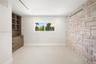 Stone accent wall, built-in wooden cabinetry featuring drawers and shelving, and a horizontal window with exterior greenery