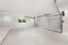 Garage interior featuring a seamless epoxy floor finish, recessed ceiling lighting, a white sectional garage door, and a single-pane window