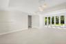 Large-format tile flooring, tray ceilings with recessed lighting, multi-globe pendant light fixture, and floor-to-ceiling glass panel doors