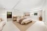 Virtually Staged: Spacious room with recessed tray ceiling, neutral stone-finish flooring, built-in shelving, pendant lighting, and sliding glass door