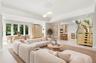 Virtually Staged: Open-concept living space featuring high tray ceilings, wood-finish cabinetry, a modern staircase with glass railings and wood tread