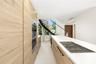 Kitchen featuring full-height wood-finish cabinetry, integrated wall oven, large island with quartz-style countertop, inset gas cooktop, and a curved 