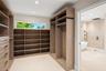 Walk-in closet featuring floor-to-ceiling wood-finish cabinetry, built-in shelving, drawers with matte black hardware, and an elongated horizontal win